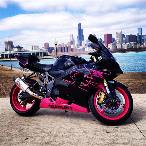 A Pink And Black Motorcycle Parked In Front Of A Body Of Water With A