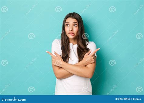 Portrait Of Indecisive Silly Girl In White T Shirt Making Decision Pointing Fingers Sideways