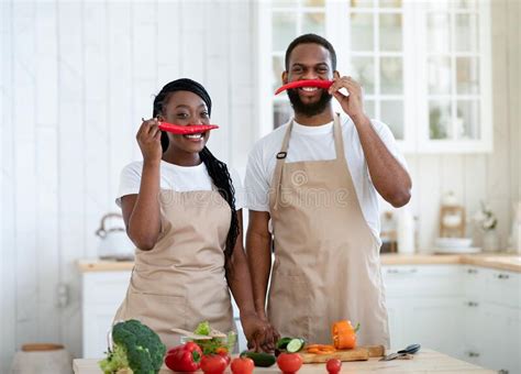 African Couple Having Fun While Cooking In Kitchen Keeping Pepper As Moustache Stock Image