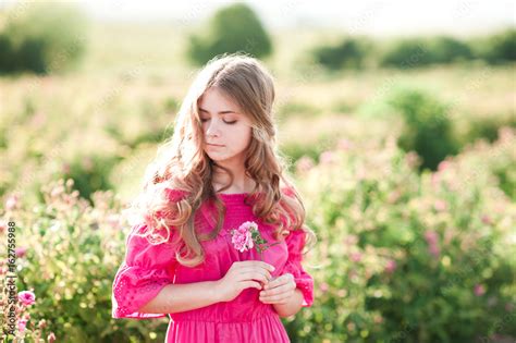 beautiful blonde teen girl 14 16 year old wearing pink dress holding rose flower outdoors