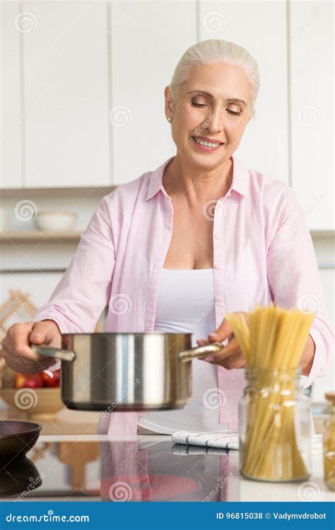 Smiling Mature Woman Standing At The Kitchen Cooking Stock Photo