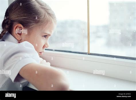One Sad Little Girl Sitting Near The Window At The Day Time Concept Of