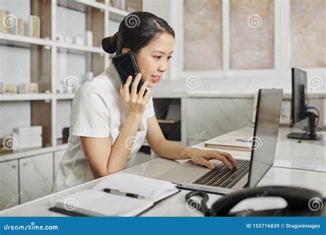 Receptionist Checking Schedule And Answering Phone Call Stock Image