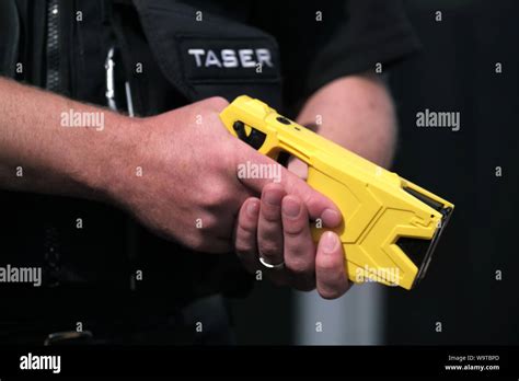 A British Police Officer Holding A Axon Taser X2 Conducted Electrical