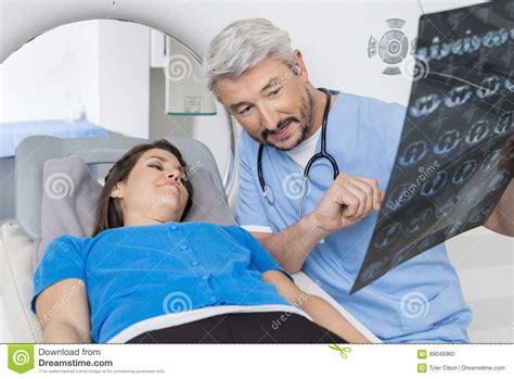 Doctor Explaining X Ray To Patient Lying On Ct Scan
