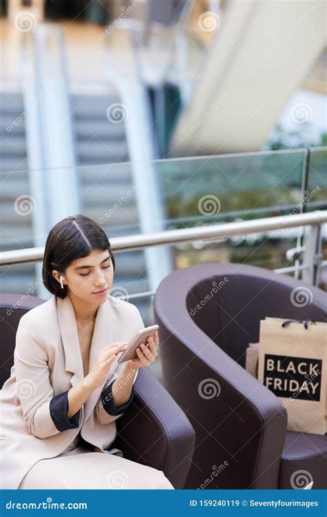 Elegant Woman Using Smartphone While Relaxing In Shopping Mall Stock