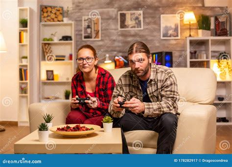 Gamers Couple Playing Video Games On The Tv With Wireless Controllers
