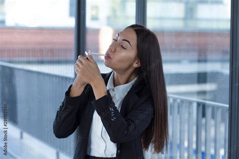 Young Business Woman Lights A Cigarette In A Smoking Room Formal
