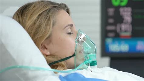 Female Patient Lying Hospital Bed With Oxygen Mask Monitor Showing