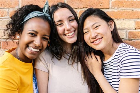 Smiling Portrait Of Three Young Diverse Female Friends Looking At