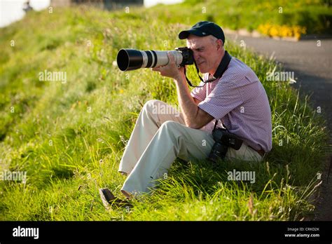 An Amateur Photographer Sitting Down Taking A Photo Photograph Using A Long Telephoto Lens Canon