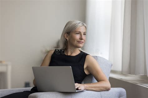 Thoughtful Positive Blonde Mature Woman Resting In Armchair Stock Image