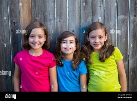 Sister And Friends Kid Girls Portrait Smiling Happy On Gray Fence Stock