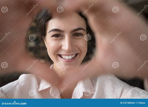 Closeup Woman Staring At Camera Through Joined Fingers Showing Love