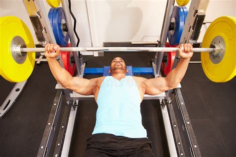 Man Flexing Muscles While Bench Pressing Weights At A Gym Stock Image