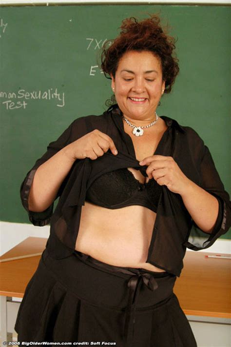 Curly Older Teacher In Black Stockings Poses On The Table