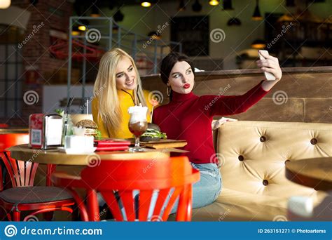 Two Joyful Cheerful Girls Taking A Selfie While Sitting Together At Cafe Stock Image Image Of