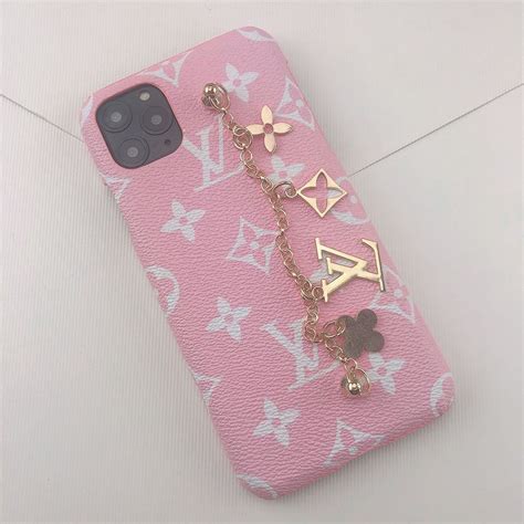 A Pink Phone Case With Charms Attached To The Back Of It Sitting On