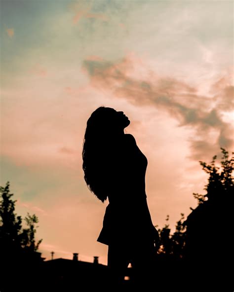 Silhouette Of Woman Standing Under Cloudy Sky During Daytime Photo