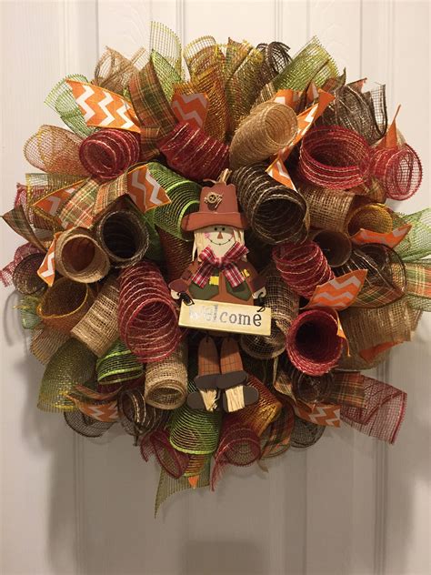 A Wreath With A Scarecrow On It Hanging From The Front Door Decorated