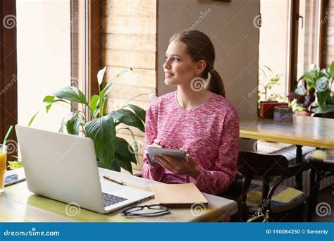 Young Freelancer With Tablet Pc And Laptop Working In Cafe Stock Photo