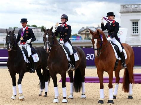 Four Equestrians Are Standing On Their Horses In An Arena