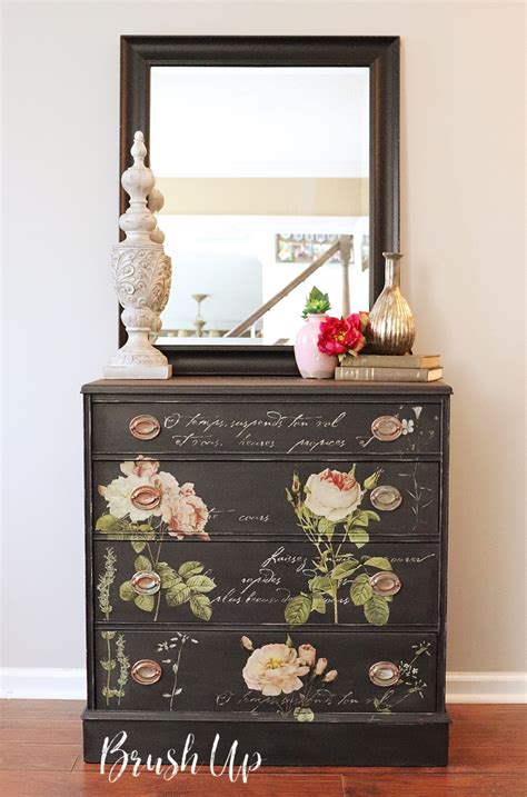 A Black Dresser With Flowers Painted On It And A Mirror Above The