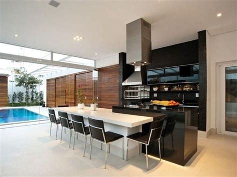 A Modern Kitchen With Black And White Furniture Next To A Swimming Pool