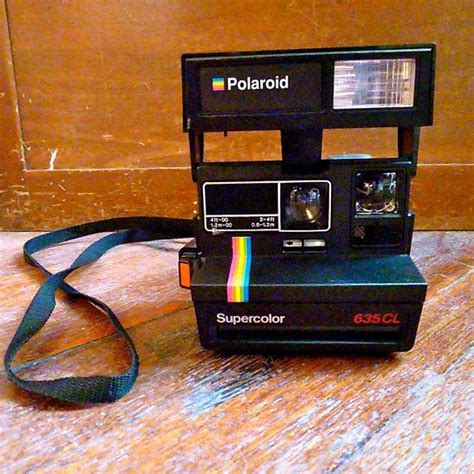 An Old Polaroid Camera Sitting On Top Of A Wooden Floor Next To A Blue