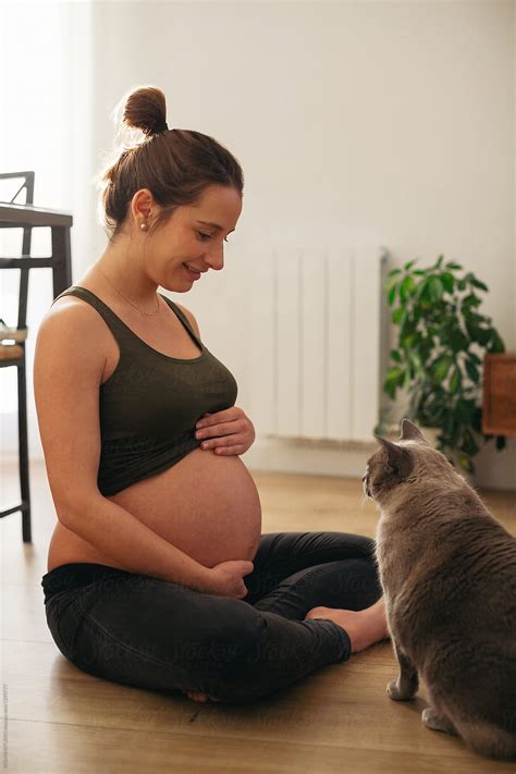 Pregnant Woman Sitting On The Floor With Her Cat At Home By Stocksy