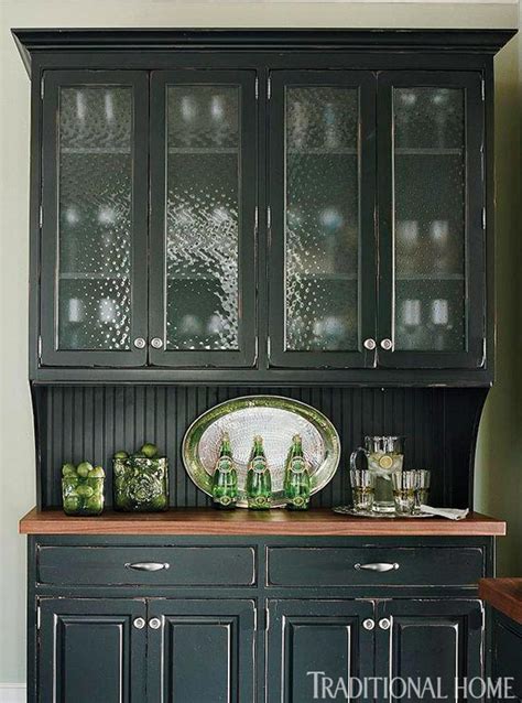Faux cabinet doors hide a kitchen vent hood placed over an integrated gas cooktop and oven placed next to floor to ceiling black pantry cabinets. Distinctive Kitchen Cabinets with Glass-Front Doors ...