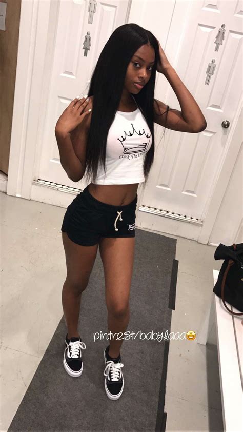a woman standing in front of a door wearing black shorts and a white crop top