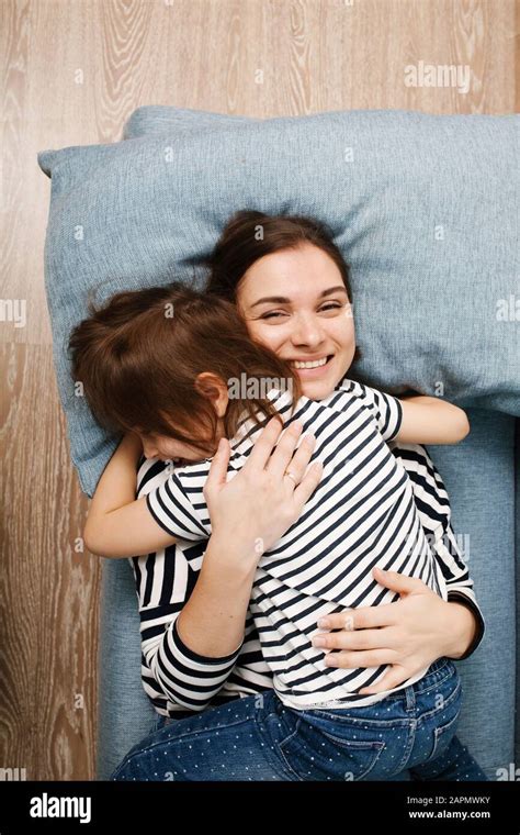 beautiful smiling mother hugging her cute little daughter mom and girl in same clothes lying