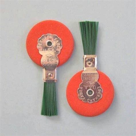 Two Orange Buttons With Green Tassels On Them