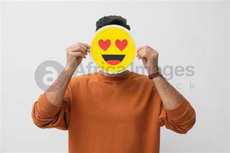 Man Hiding Emotions Using Card With Drawn Smiling Face On White