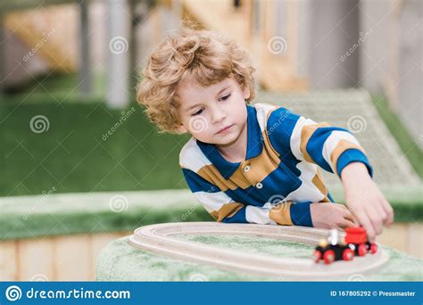 Adorable Little Boy Lying On The Floor Of Playground While Playing Toy