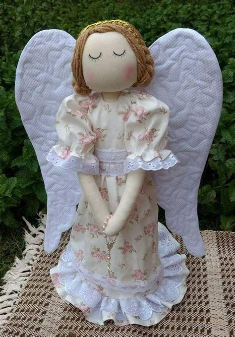 An Angel Figurine Sitting On Top Of A Table Next To Some Bushes And Grass