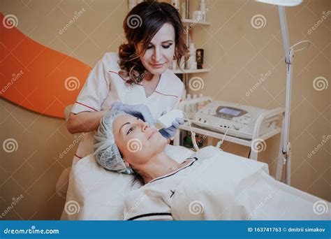 Cosmetology Doctor Makes The Procedure A Woman Face Cleaning Stock