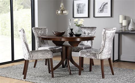 A dining table, seating, and a storage/display. Hudson Round Dark Wood Extending Dining Table with 4 Bewley Silver Velvet Chairs | Furniture Choice
