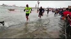 Marathon runners splash through flooded street