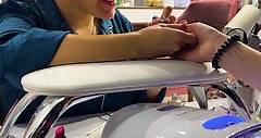 Una ragazza bacia le unghie della sua cliente al salone di manicure