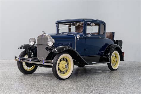 A pristine 1930 Ford Model A Coupe parked on a scenic road, showcasing its classic design.