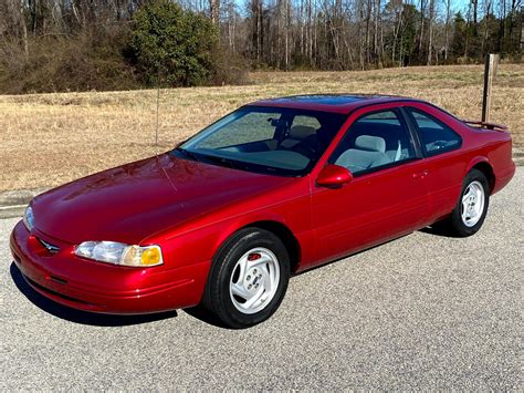 A sleek 1997 Ford Thunderbird parked on a scenic road, showcasing its classic design.