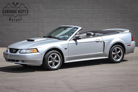 A sleek, red 2000 Ford Mustang GT parked on a scenic road