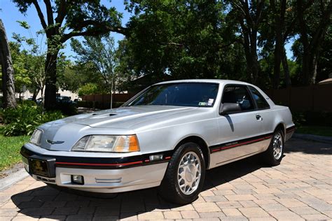 A classic 1988 Ford Thunderbird parked on a scenic road