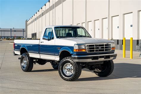 A rugged 95 Ford F250 pickup truck parked on a dirt road, showcasing its classic design and capability