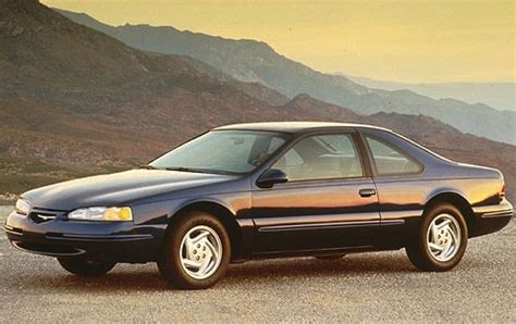 A pristine 1996 Ford Thunderbird parked on a scenic road, showcasing its classic coupe design.