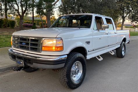 A classic 97 Ford F250 parked on a gravel driveway, showcasing its rugged exterior and powerful stance.