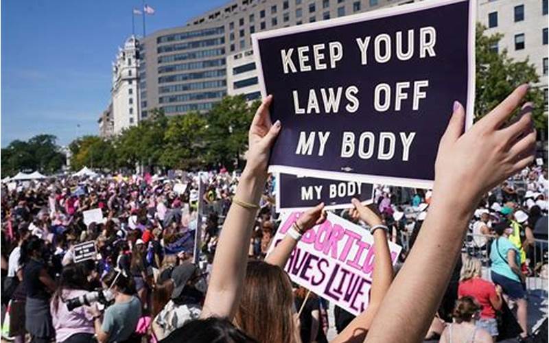 A Meme With A Picture Of A Group Of People Holding Signs That Say, 'Keep Your Laws Off My Body'