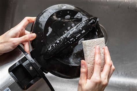 A woman cleaning a rice cooker with a sponge